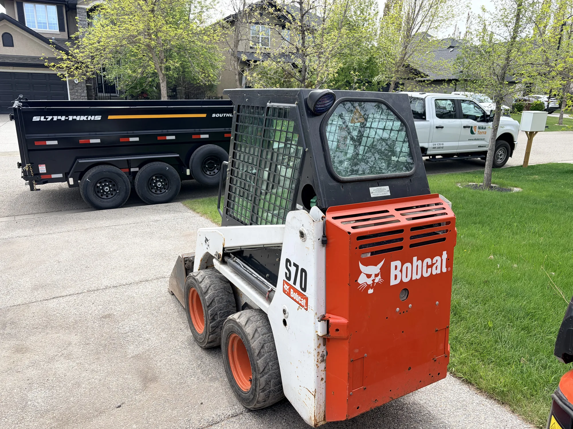 Mini skid steer with auger attachment drilling post holes in Calgary