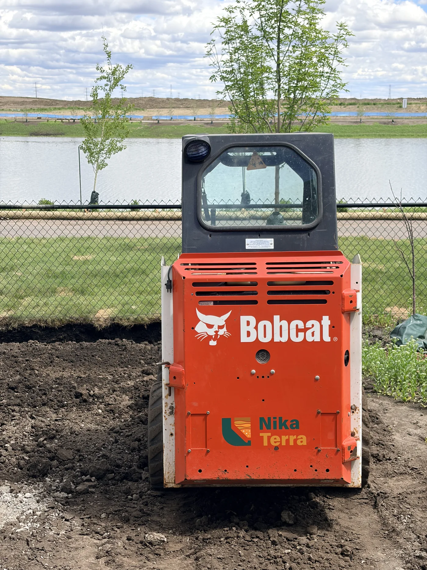 Compact equipment grading soil near a Calgary backyard drainage corridor