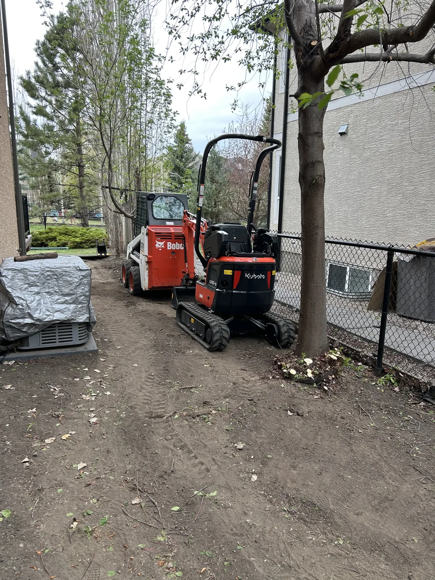 Mini excavator and skid steer working in a tight Calgary side yard