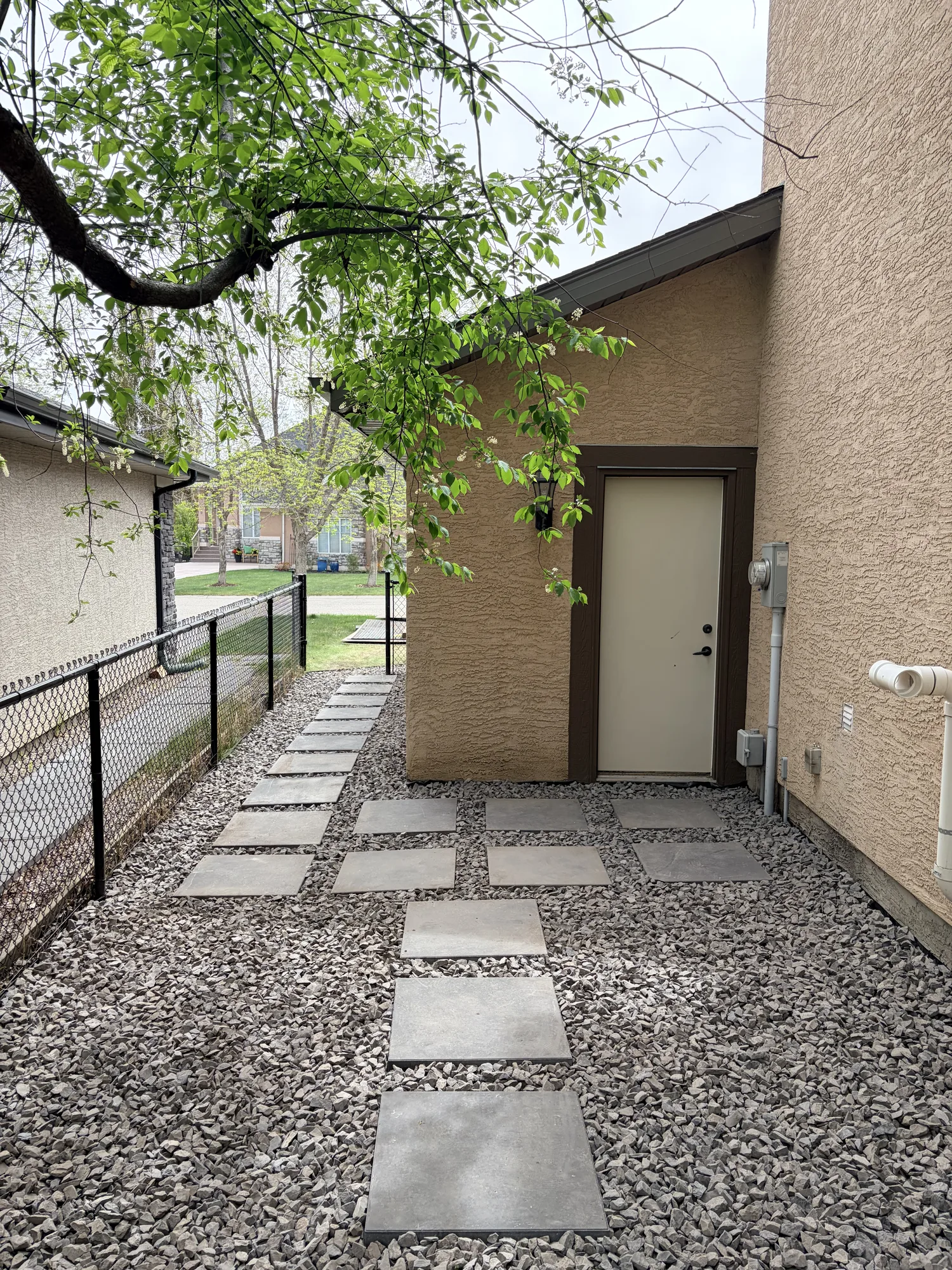 Finished Calgary side yard with concrete stepping stones set in decorative rock leading to the home entry