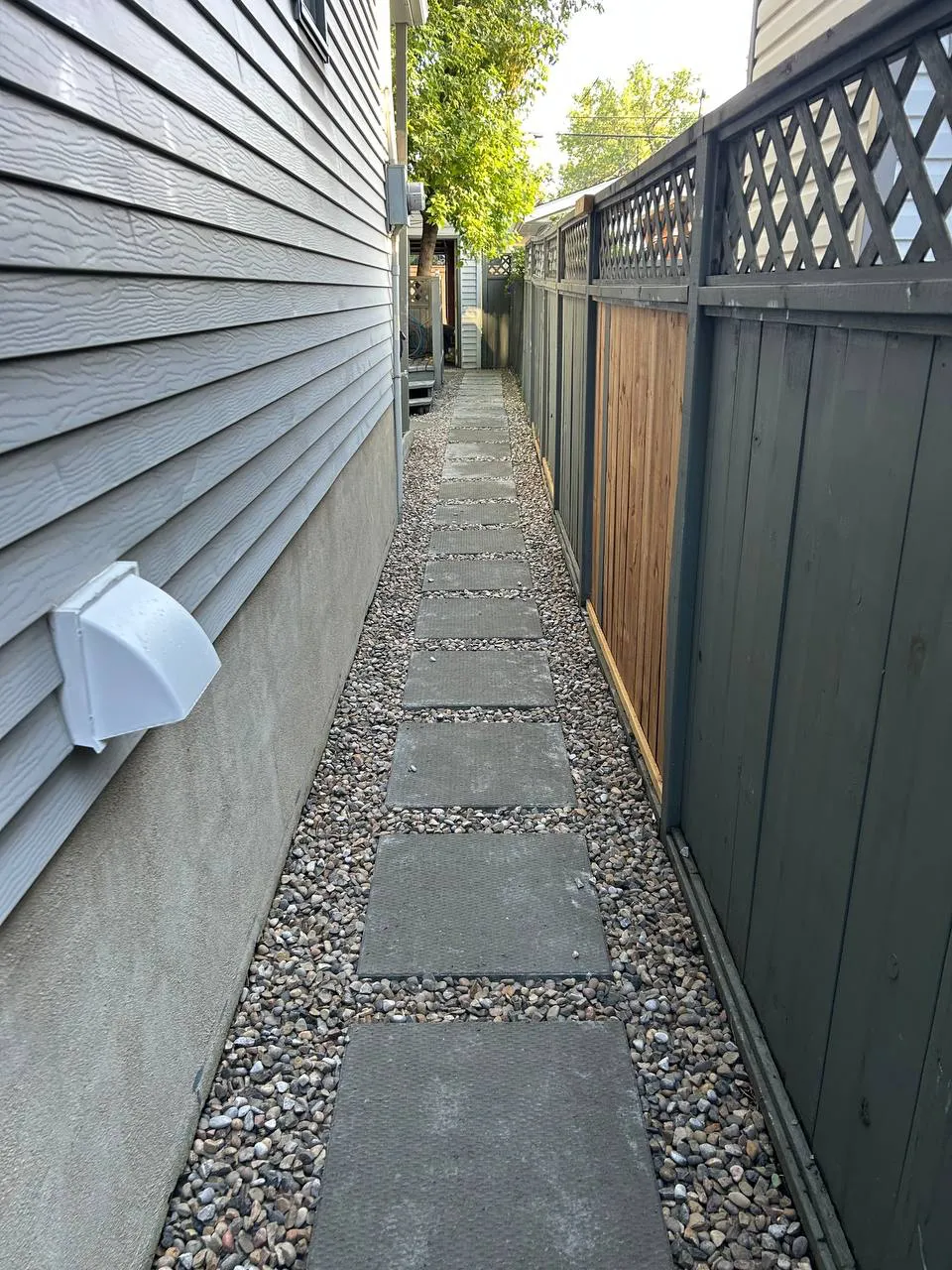 Decorative rock around square stepping stones in a Calgary side yard